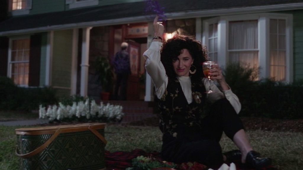 Agatha controlling fake Pietro while she sits on the lawn with a glass of wine.